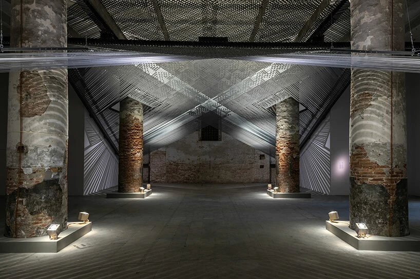 Installation view of Takapau by Mataaho Collective at La Biennale di Venezia, featuring woven polyester tie-downs and metal fittings suspended within a brick-columned exhibition space.