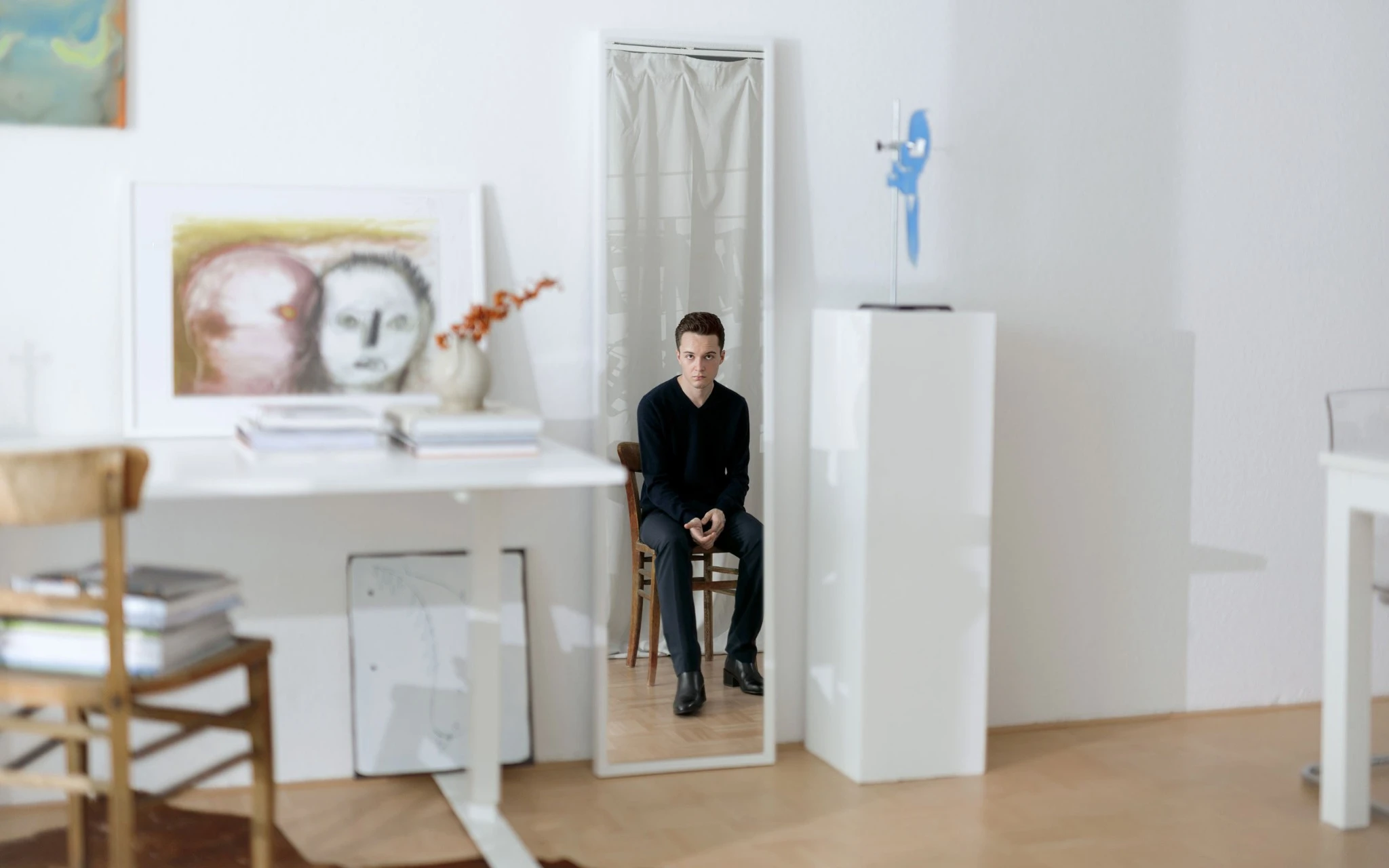 Portrait of art collector Lukas Jakob seated inside a minimalist interior surrounded by artworks and display plinths.