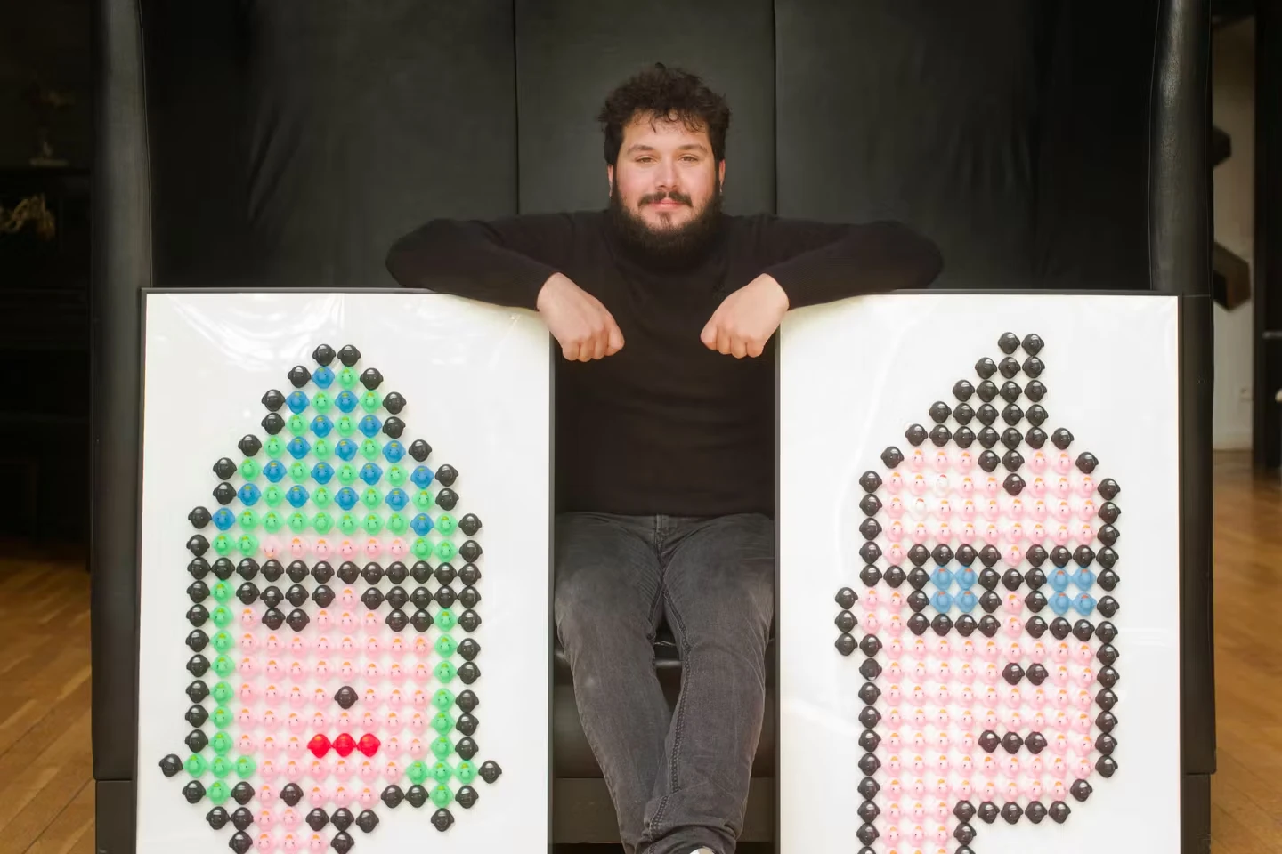 News photograph of NFT collector Brian Beccafico standing with digital artworks from Odile Finck’s CryptoPunks series in an interior setting.