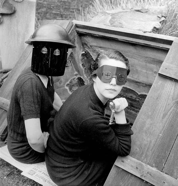 Lee Miller wearing protective goggles beside soldier in helmet and face shield, WWII era