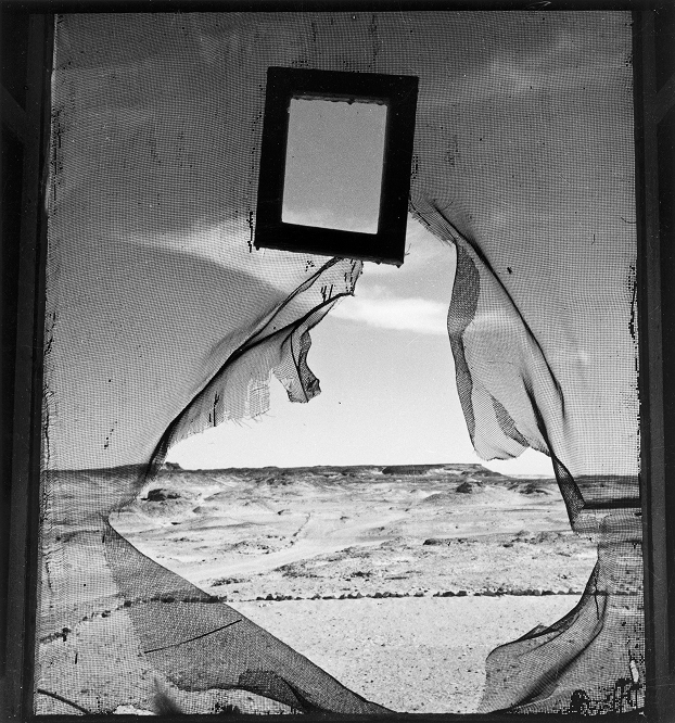 Lee Miller surrealist black and white photo, torn screen framing desert landscape with small mirror