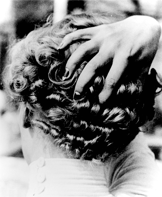 Black and white photo of curly updo hairstyle with hand resting on head, Lee Miller
