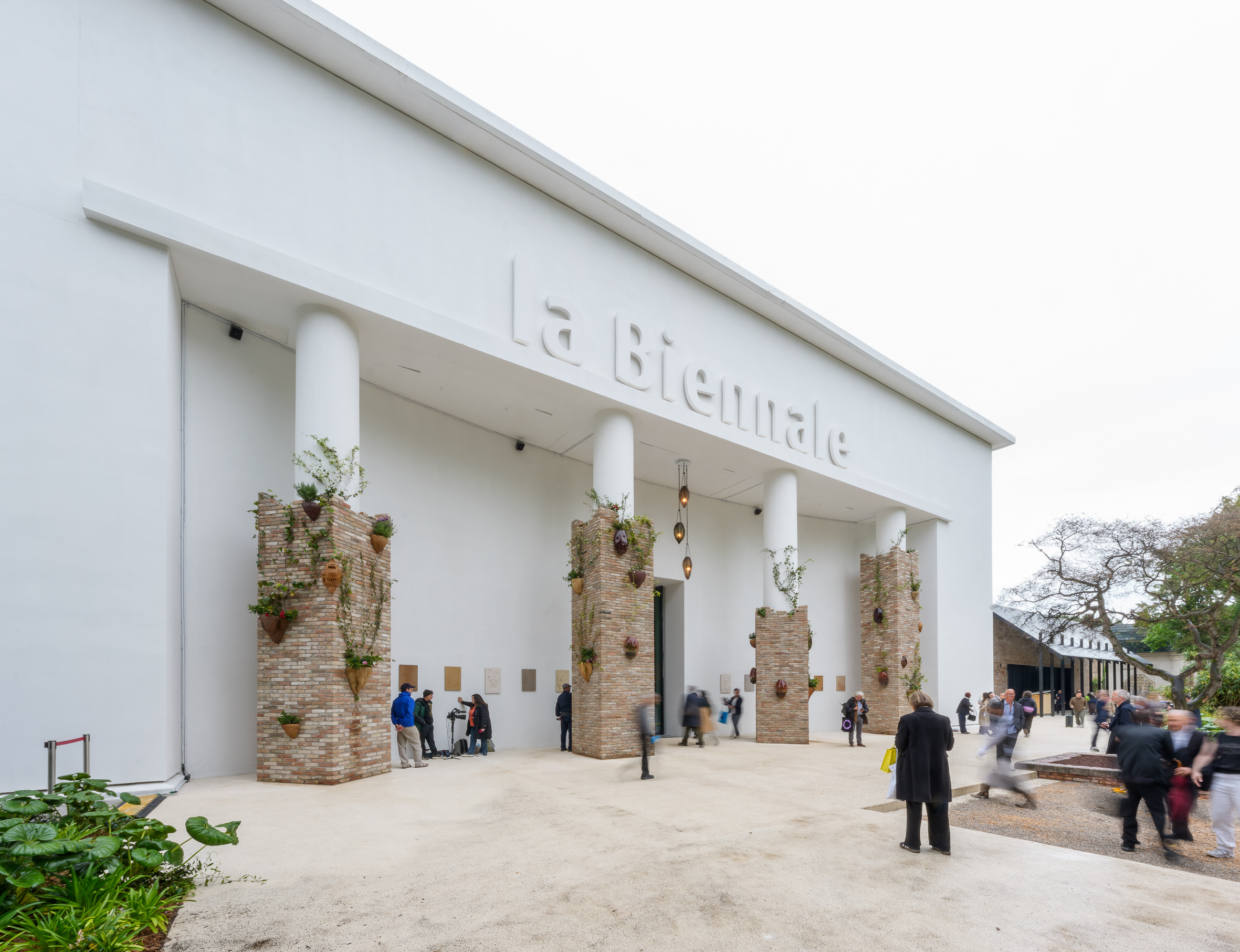 La Biennale di Venezia main entrance with brick columns, plants, and visitors