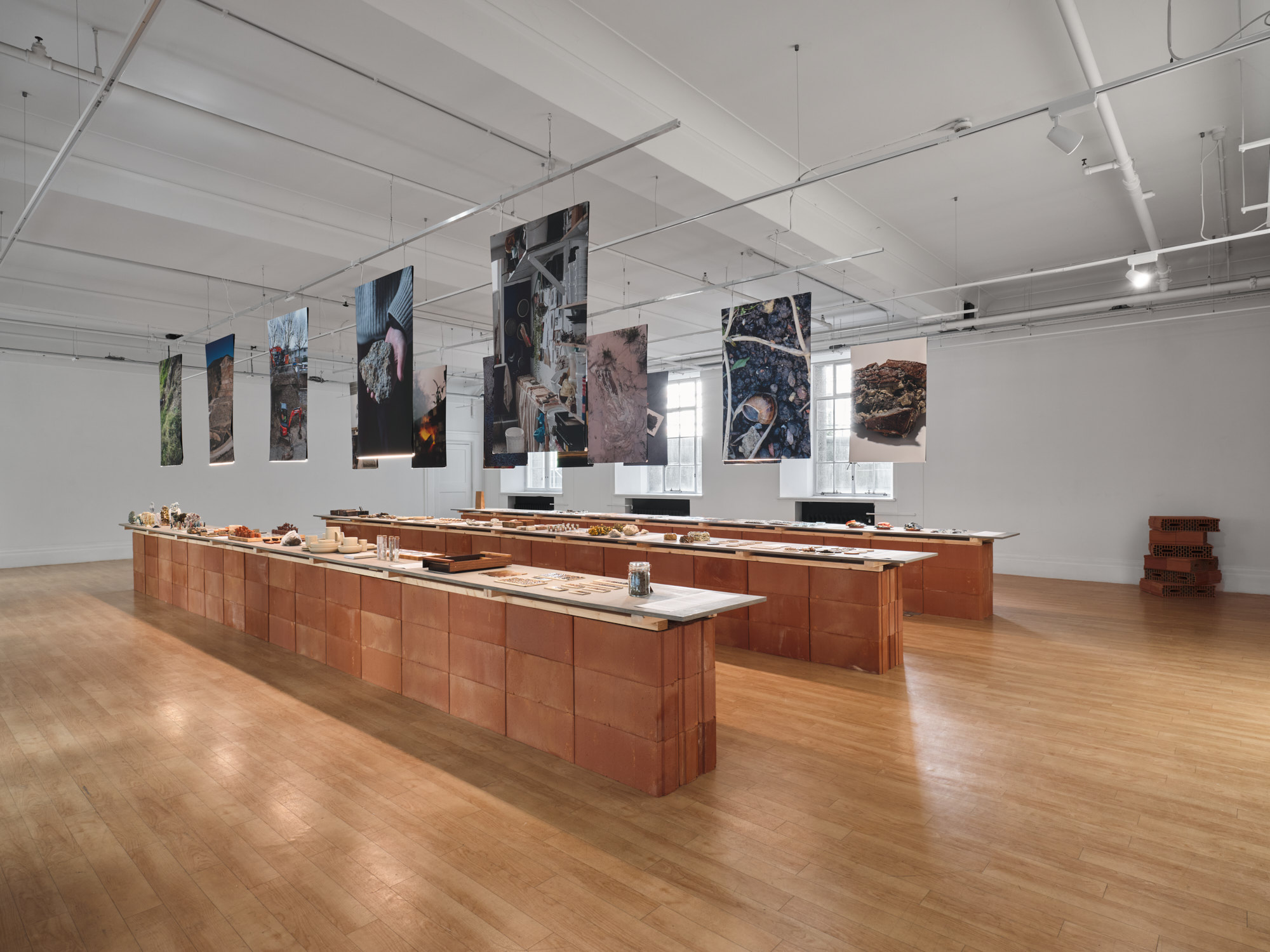 GLOST Glaze London art installation with hanging photographic banners and terracotta brick display tables in gallery