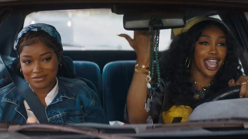 Keke Palmer and SZA laughing together in a car scene from One of Them Days