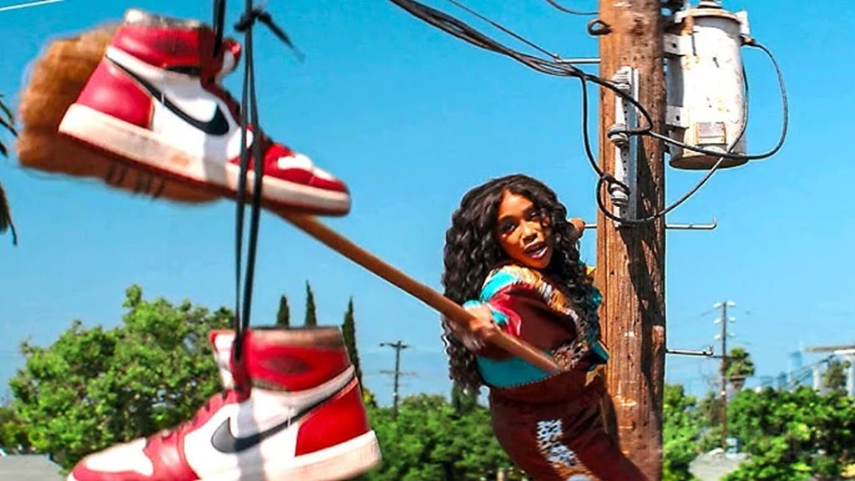 Alyssa swings a stick at oversized Nike Jordan sneakers hanging from power lines in One of Them Days