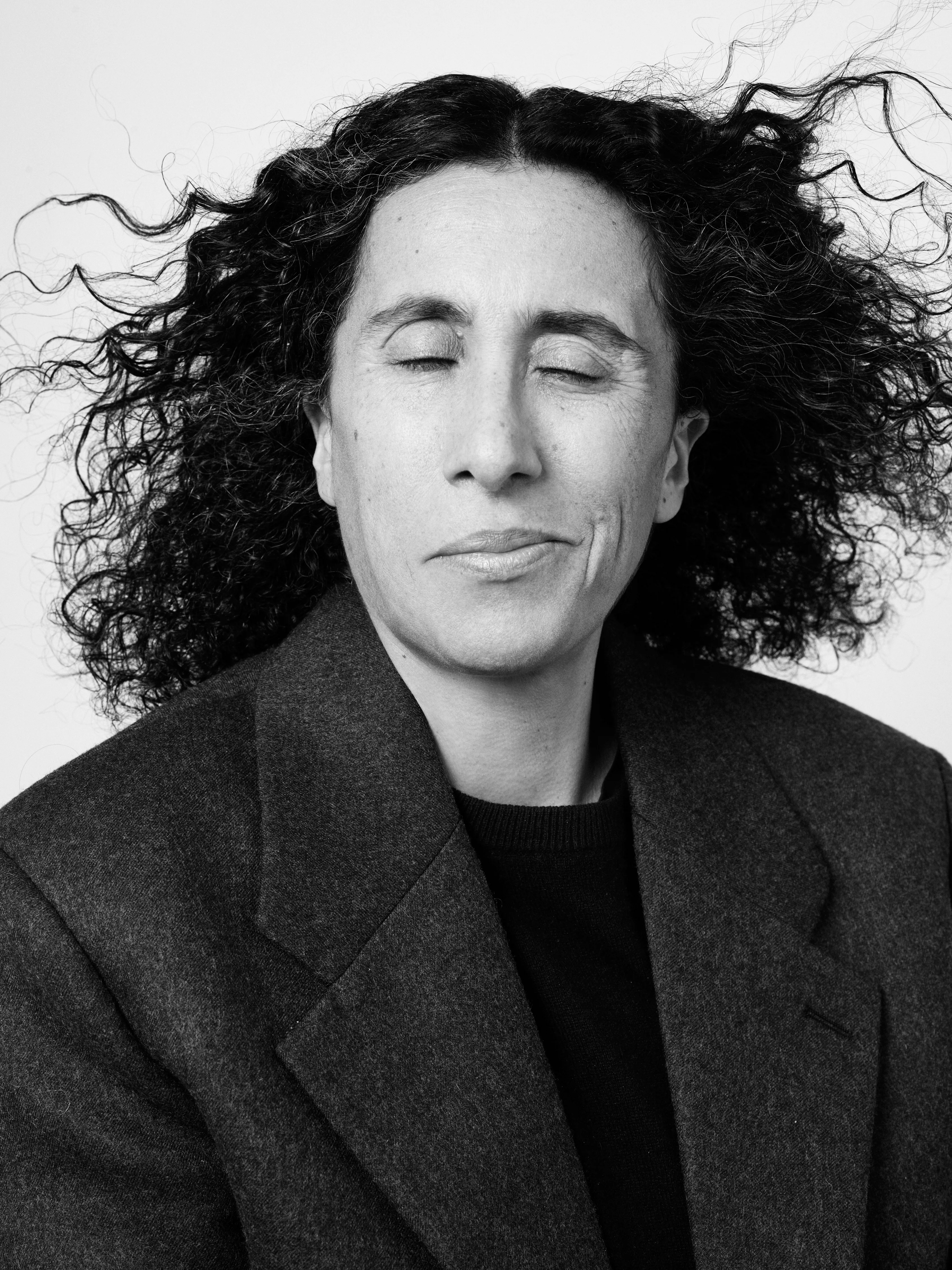 Sara Sozzani Maino black-and-white portrait with flowing curly dark hair, eyes closed, photographed by Illya Ovchar 2024