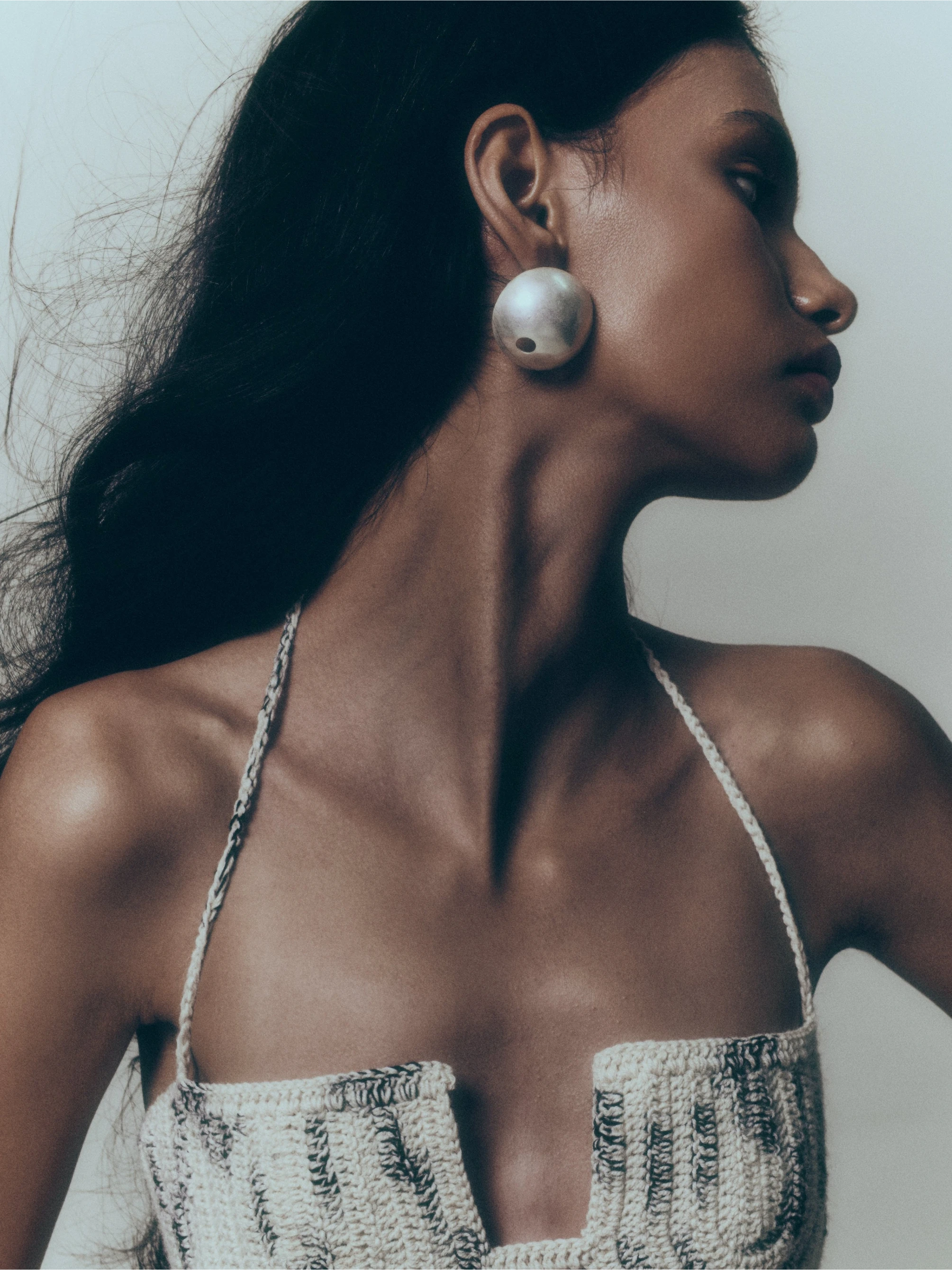 Jakhu Studio model wearing oversized silver dome earring and crochet halter top, side profile editorial shot