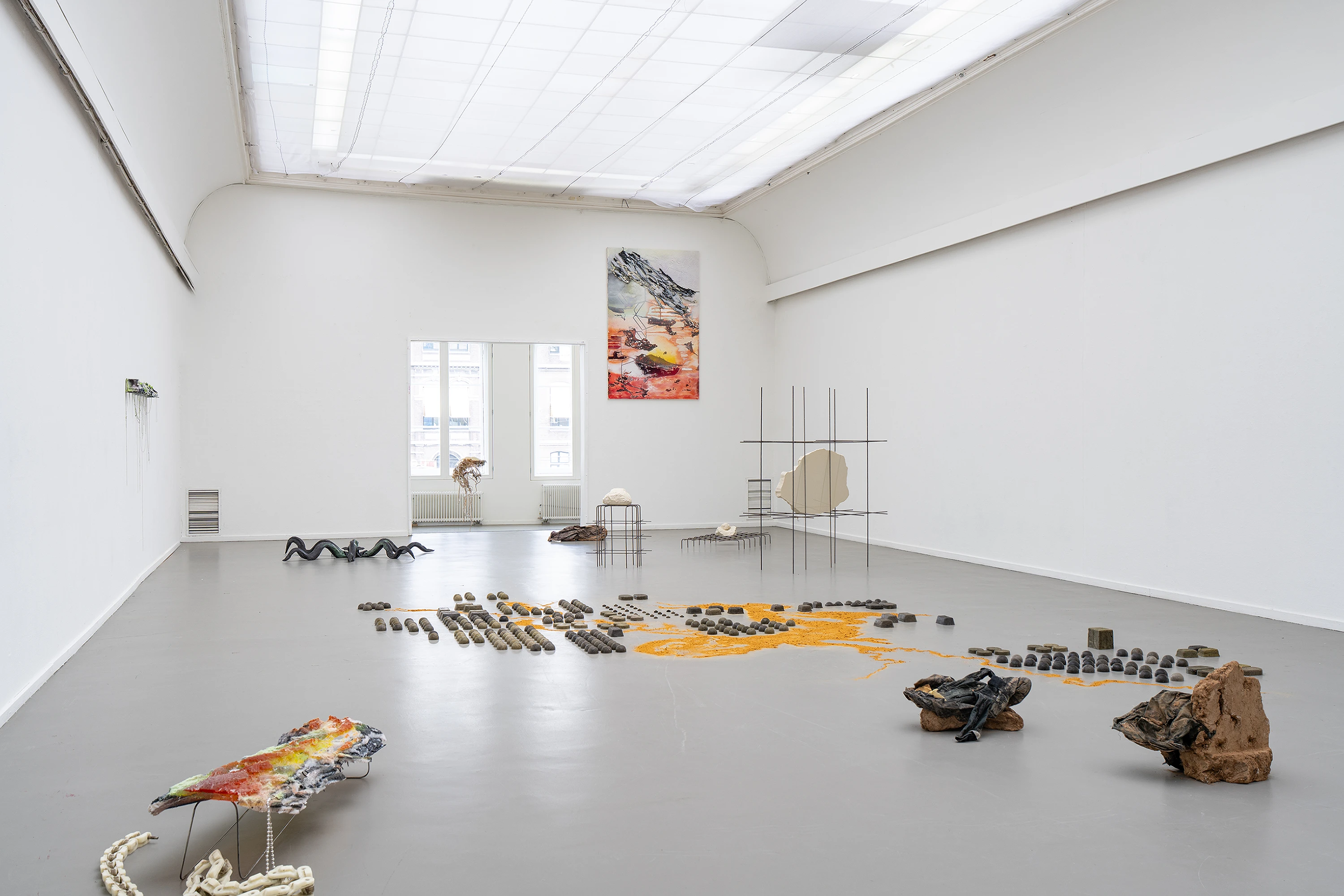Strata Strolling installation view featuring rocks, minerals, sculptures, and a landscape painting in a white gallery space