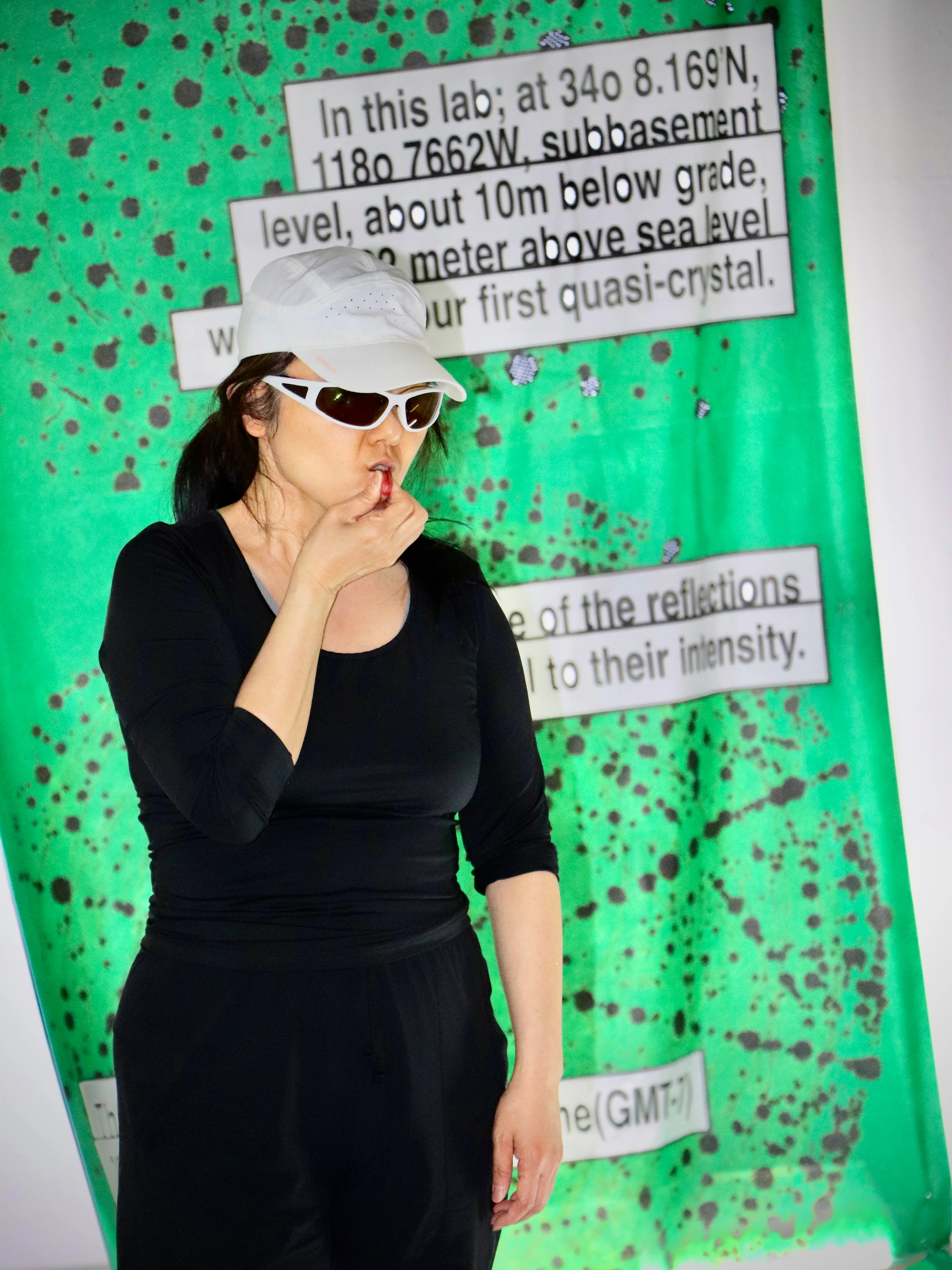 Performer in white cap and sunglasses stands before green text-printed backdrop at ReSister Korea x Irene de Boer CICA Museum exhibition