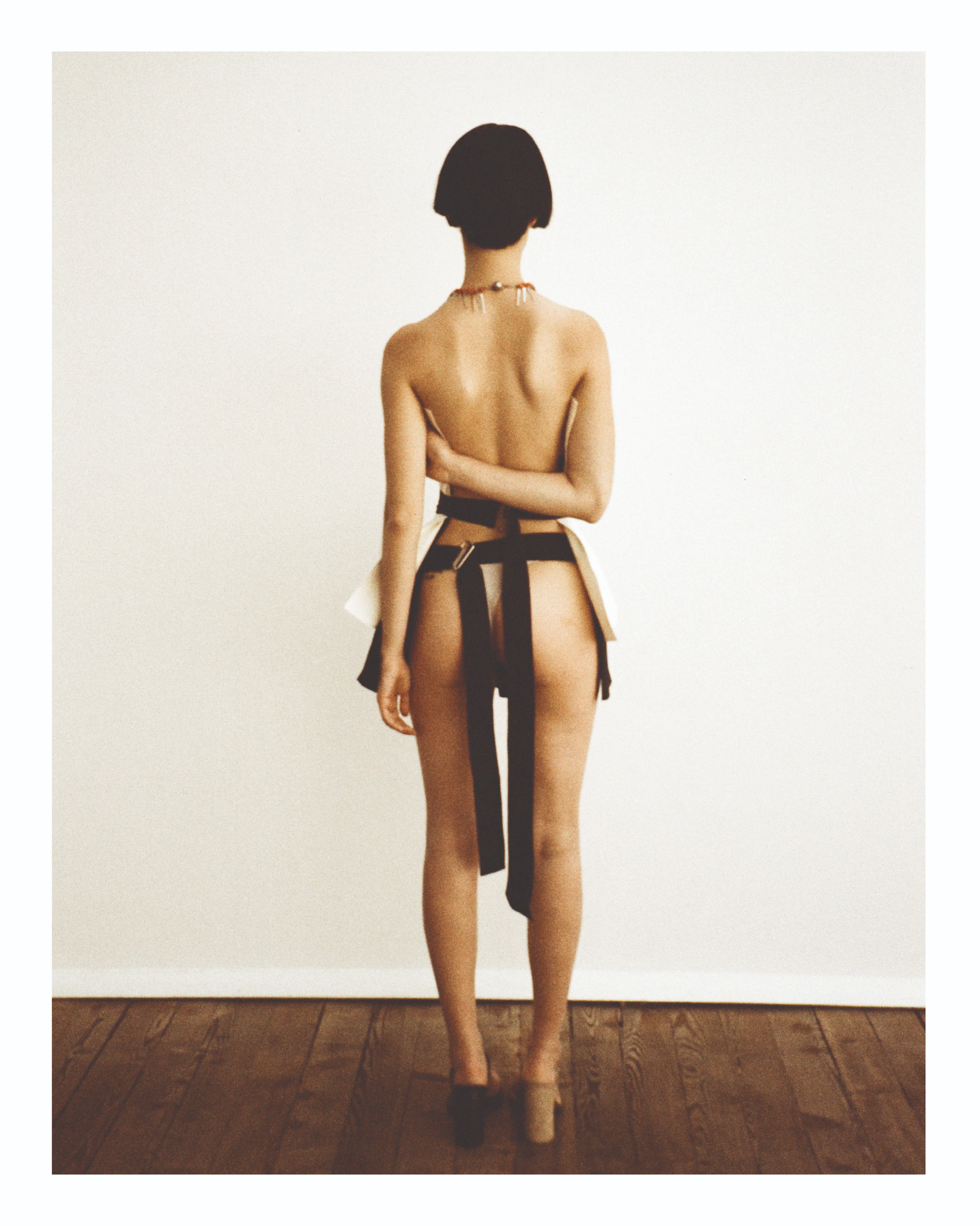 Maria Calderara Xilema SS27 backless halter look with black belt drape on wood floor