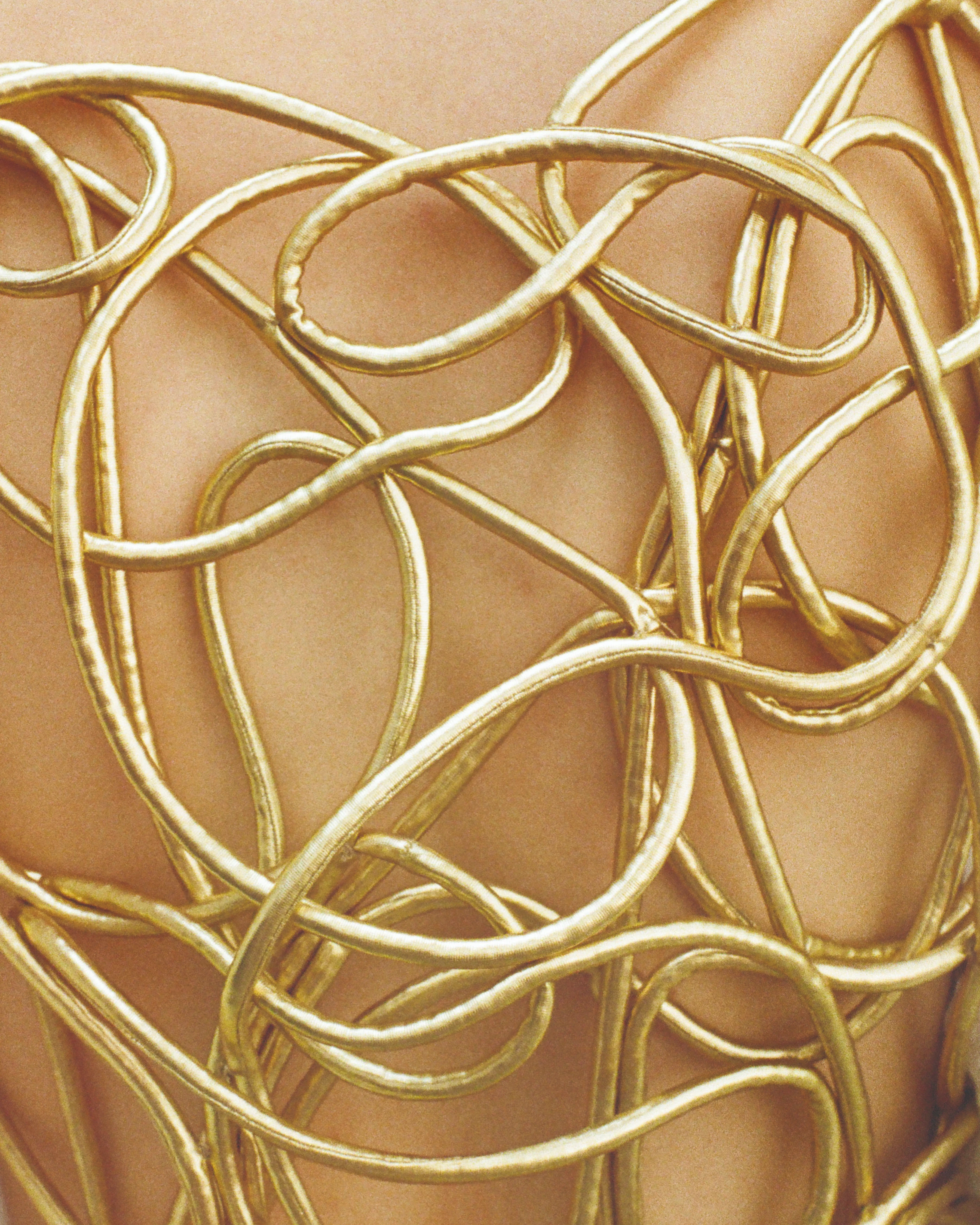 Maria Calderara Xilema SS27 gold sculptural wire bodypiece coiled in organic looping forms against bare skin