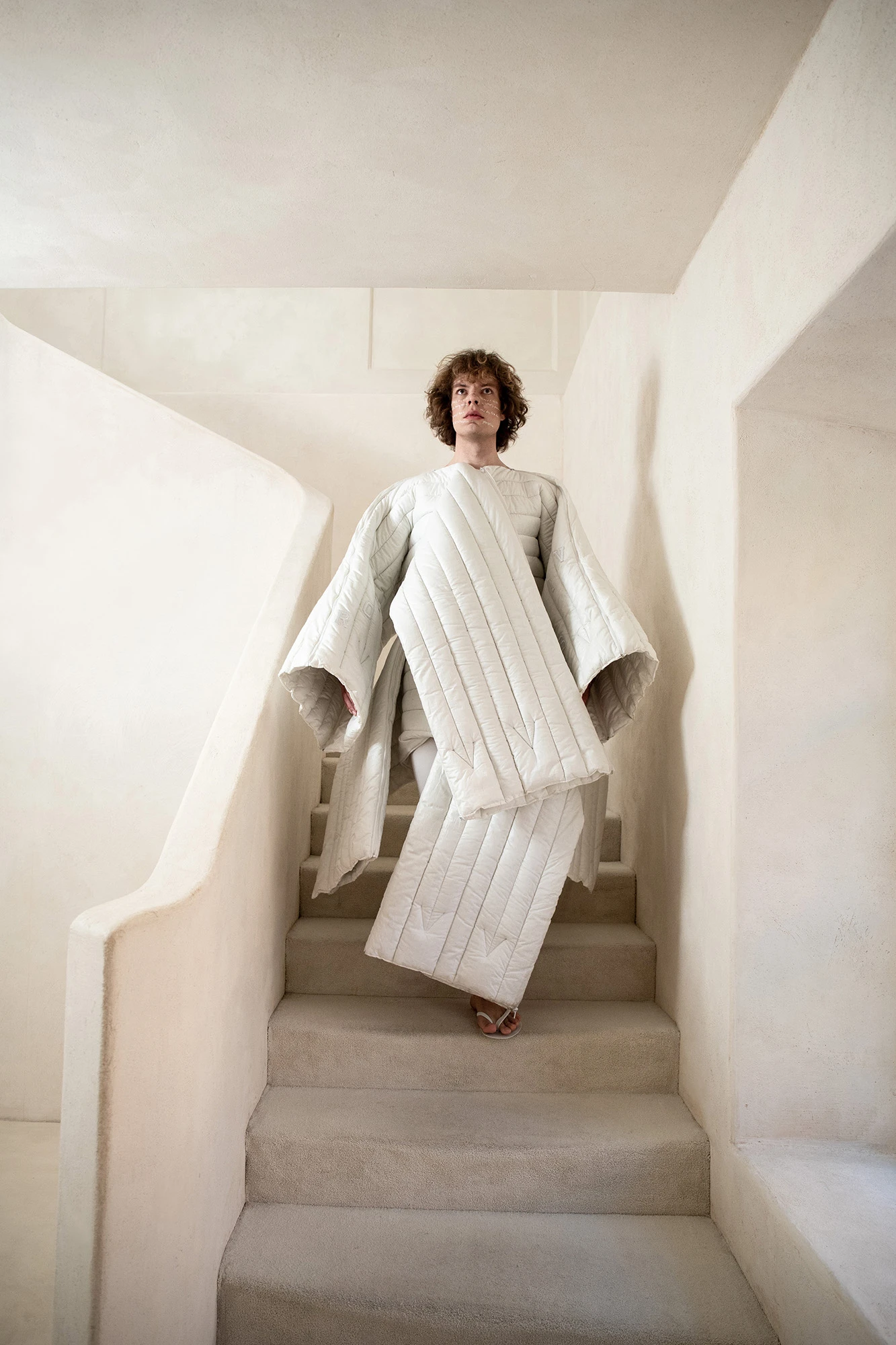 DZHUS ANTICON collection quilted white sculptural coat on model descending stairs at CONCEPT 11 Warsaw