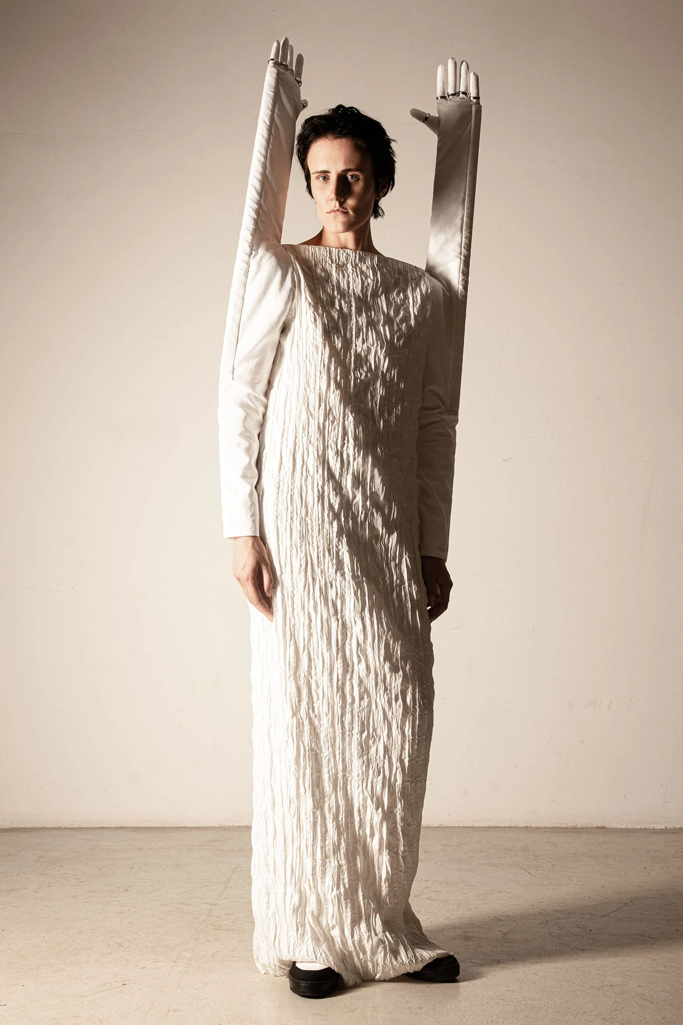 DZHUS SS24 THESAURUS collection white crinkled maxi dress with long opera gloves raised overhead, editorial fashion
