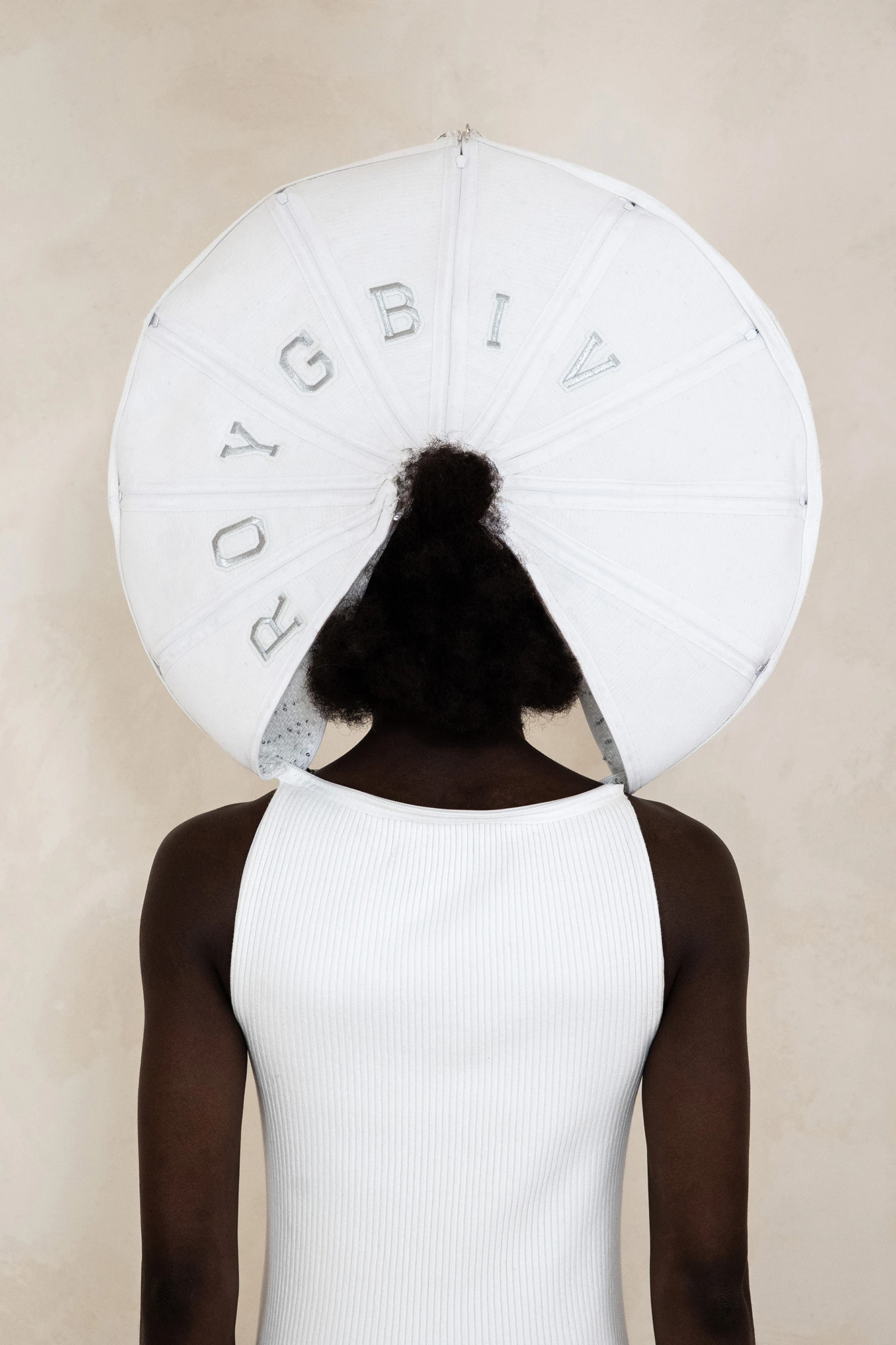 DZHUS ANTICON collection model wearing oversized white circular headpiece with ROYGBIV lettering, photographed by Marta Chudek