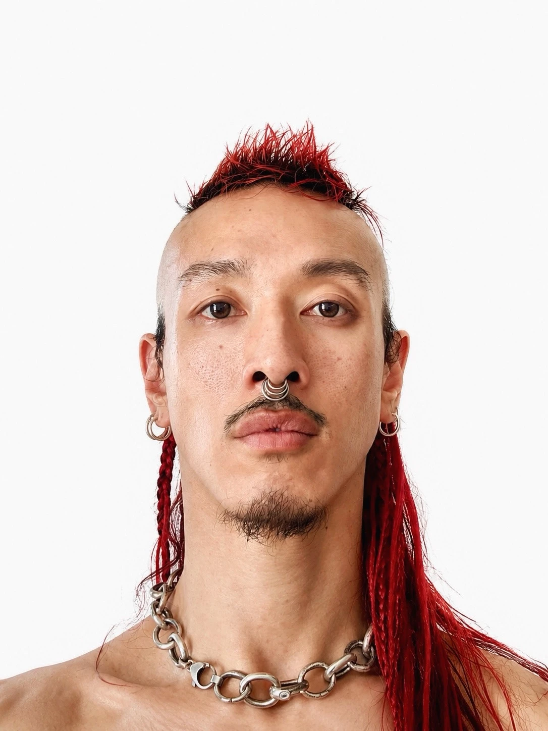 James Vu Anh Pham with red mohawk braids, septum ring, hoop earrings, and silver chain necklace
