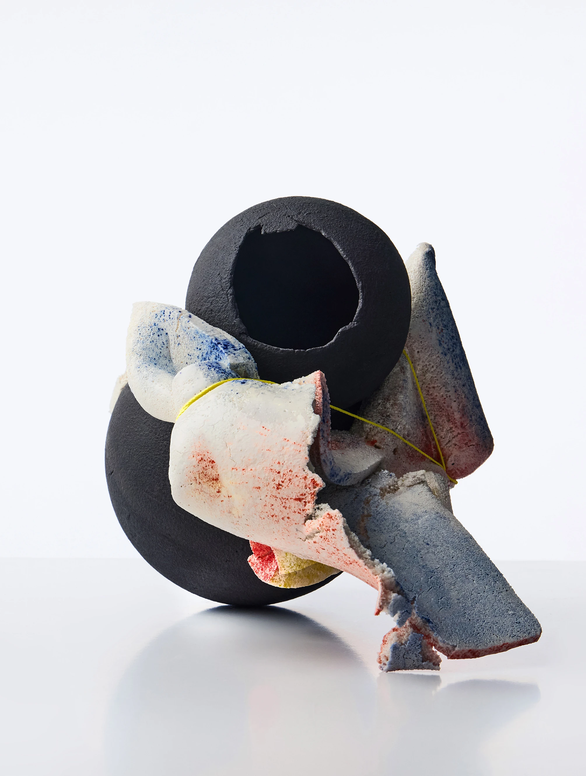 Abstract ceramic sculpture with matte black toroid form and fragmented colorful shards, From Fragility to Stability Series