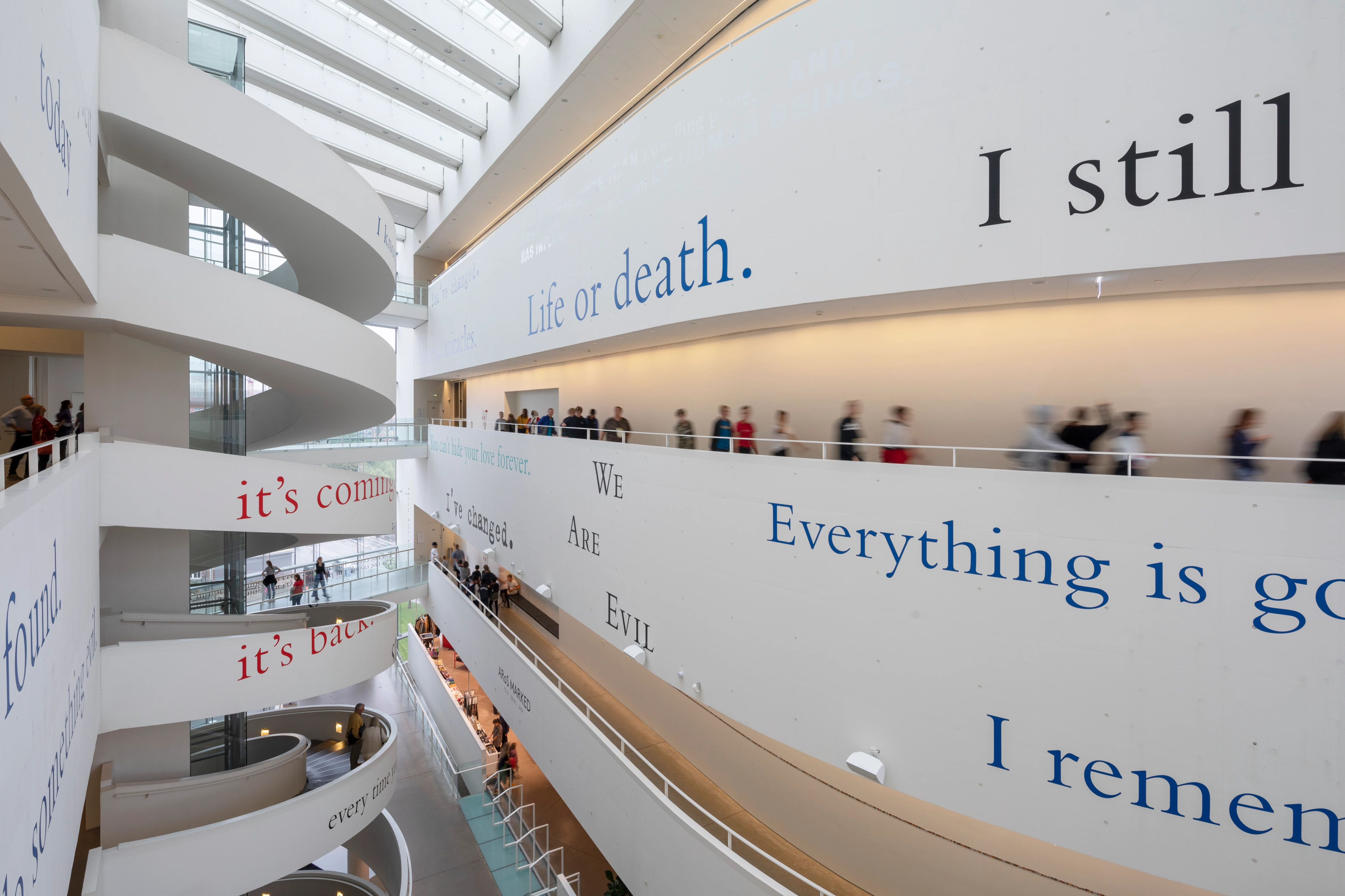 Douglas Gordon's 'In My Shadow' installation at ARoS Aarhus Art Museum, 2019, with text phrases spiraling across curved white atrium walls