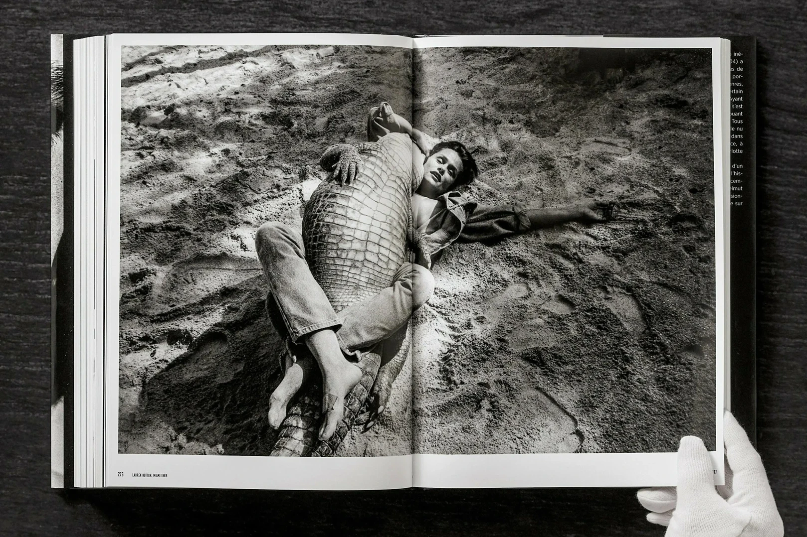 Helmut Newton Legacy Taschen book spread: black-and-white photo of person lying with crocodile on sand