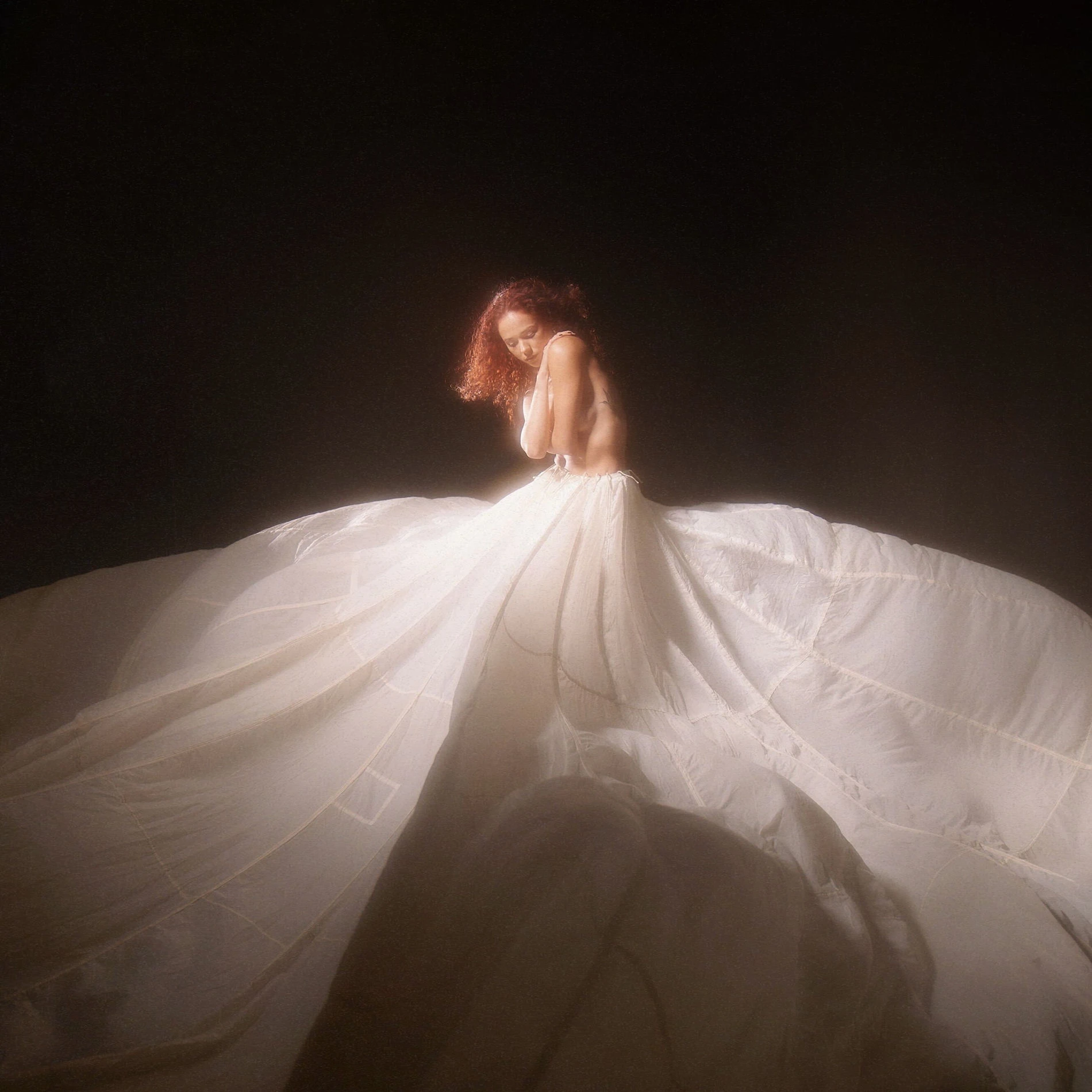 Breanna YDE in flowing white ballgown, head bowed, Parachute single cover art against dark background