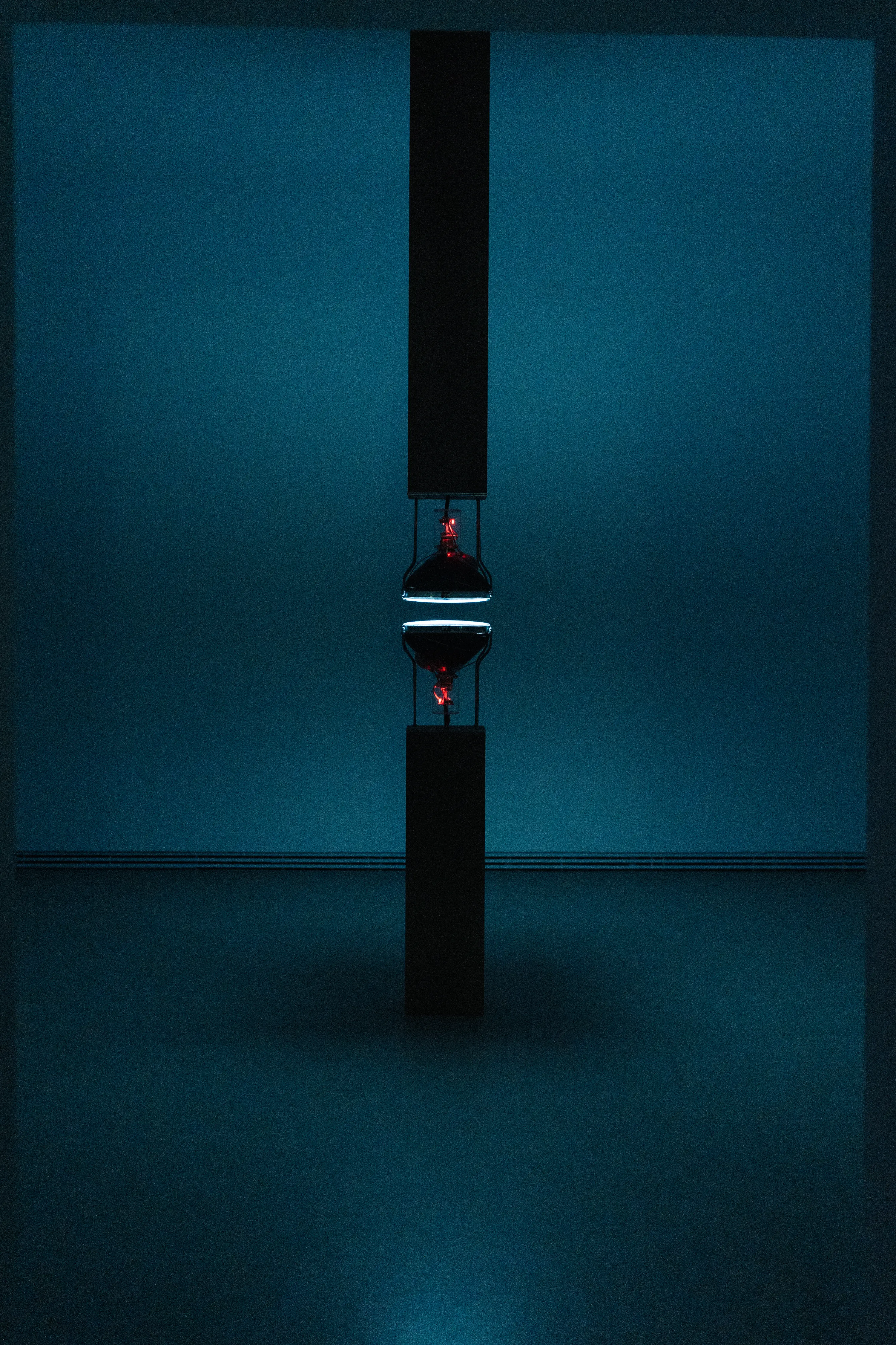 Bill Viola video installation glowing hourglass red light dark teal atmospheric gallery artwork