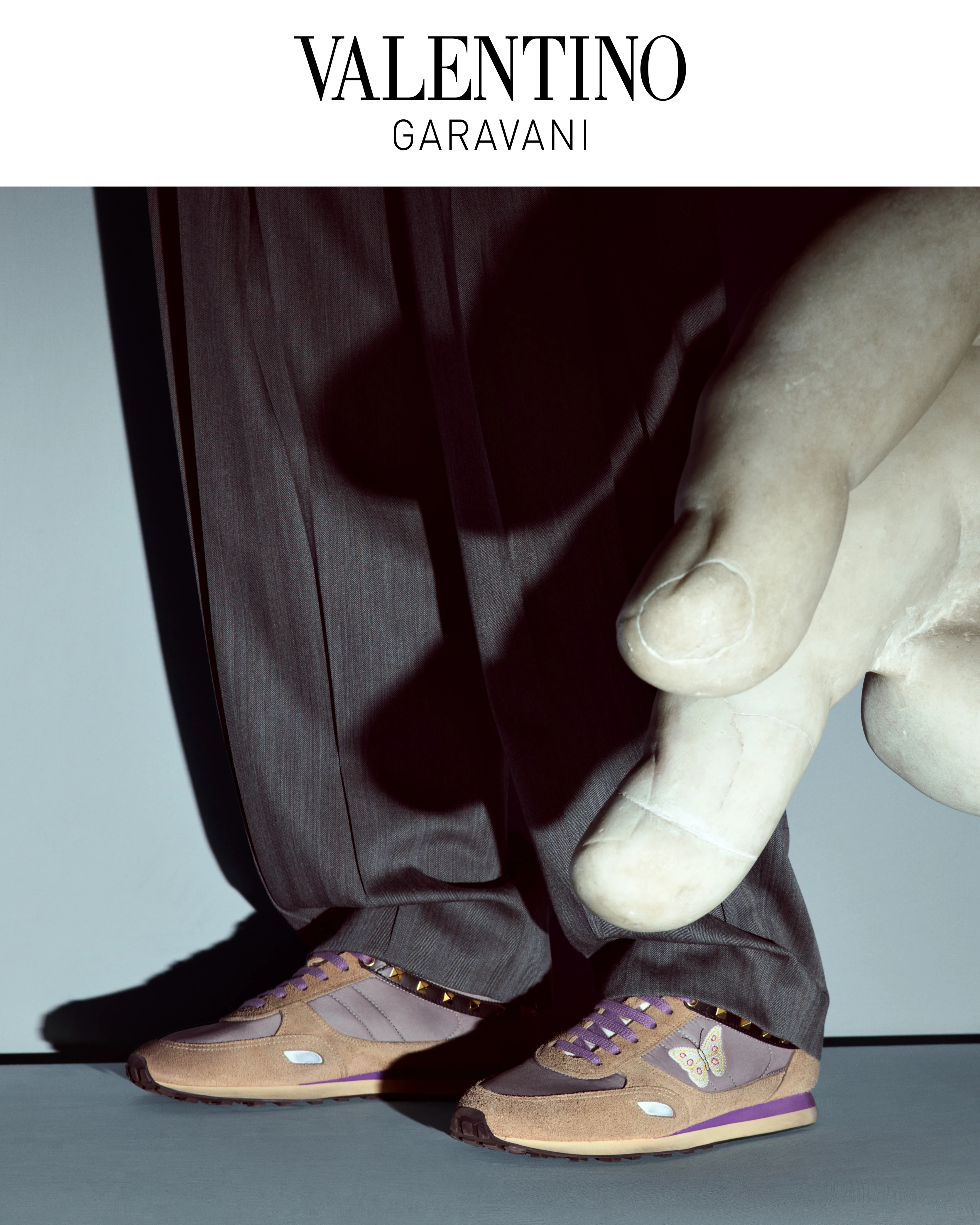 Valentino Garavani FW26 sneakers in tan suede and purple with butterfly detail, styled with dark trousers