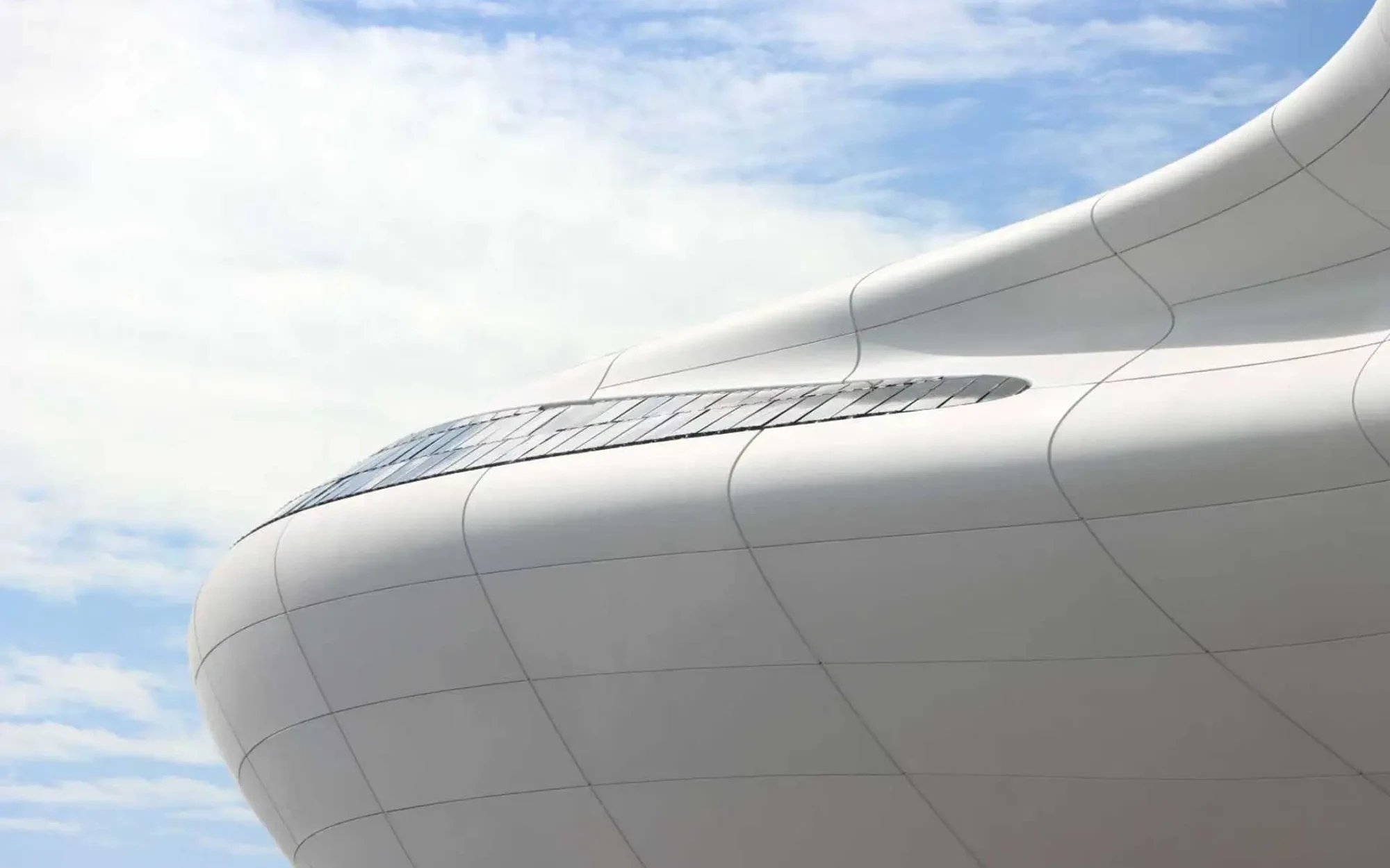 Sweeping white curved facade panels of the Lucas Museum of Narrative Art against a blue sky