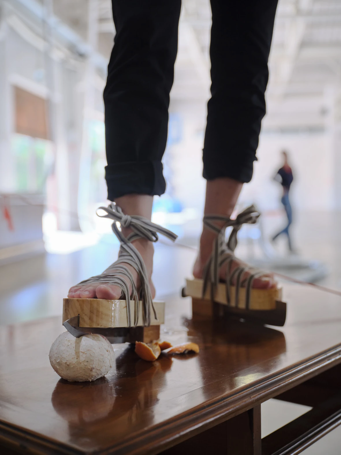 Aki Sasamoto performing Secrets of My Mother's Child, wooden platform sandals crushing food on a table, Pirelli HangarBicocca Milan 2026