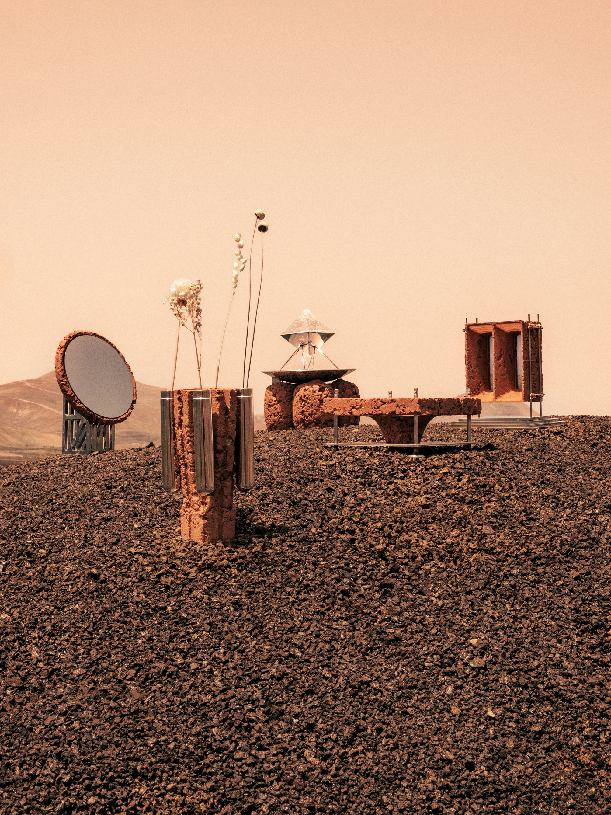 Roc H Biel Martian Relics Collection — sculptural objects arranged on volcanic terrain under a hazy peach sky