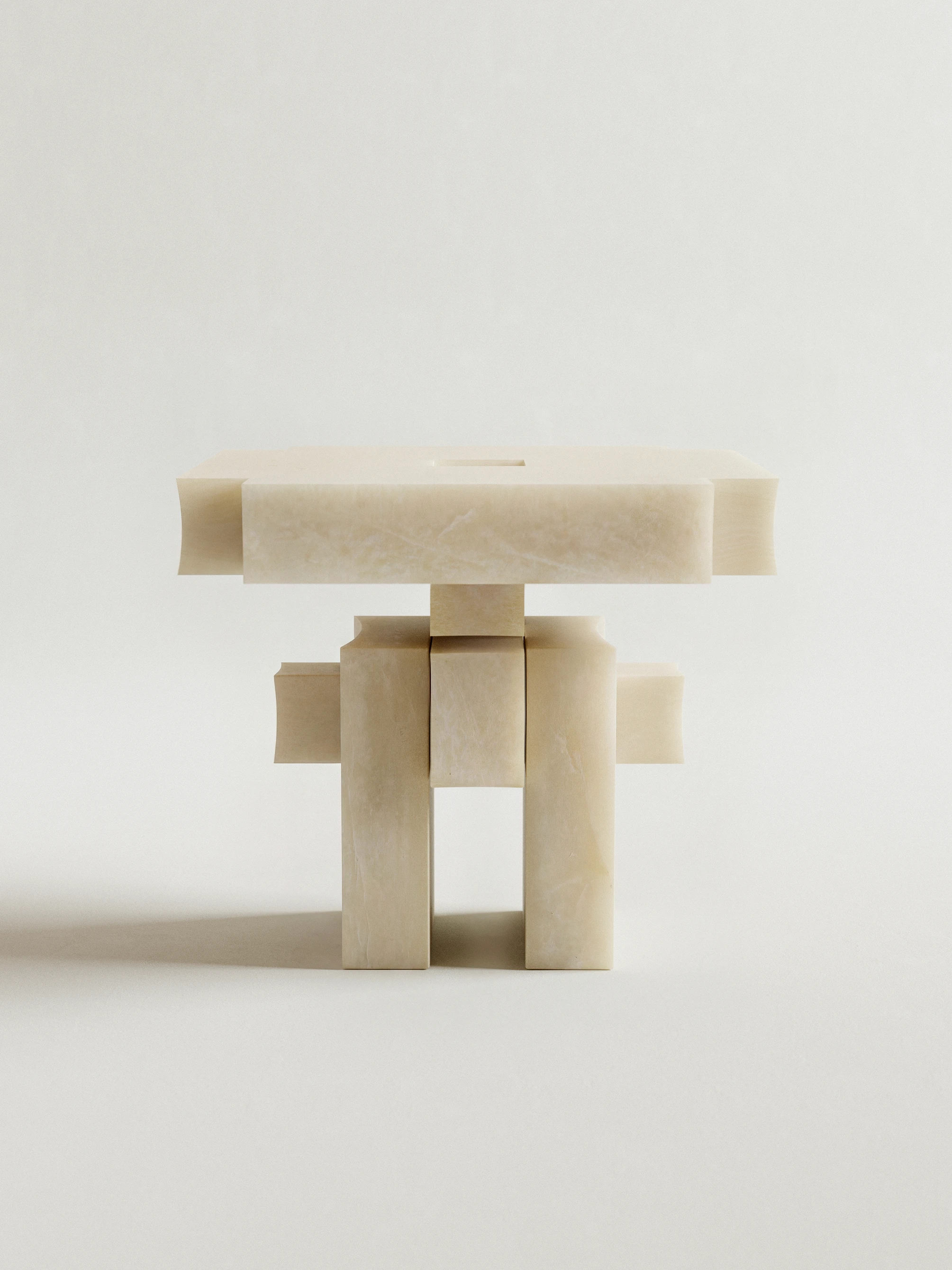 Sculptural alabaster side table with geometric interlocking block legs, minimalist brutalist design in cream stone