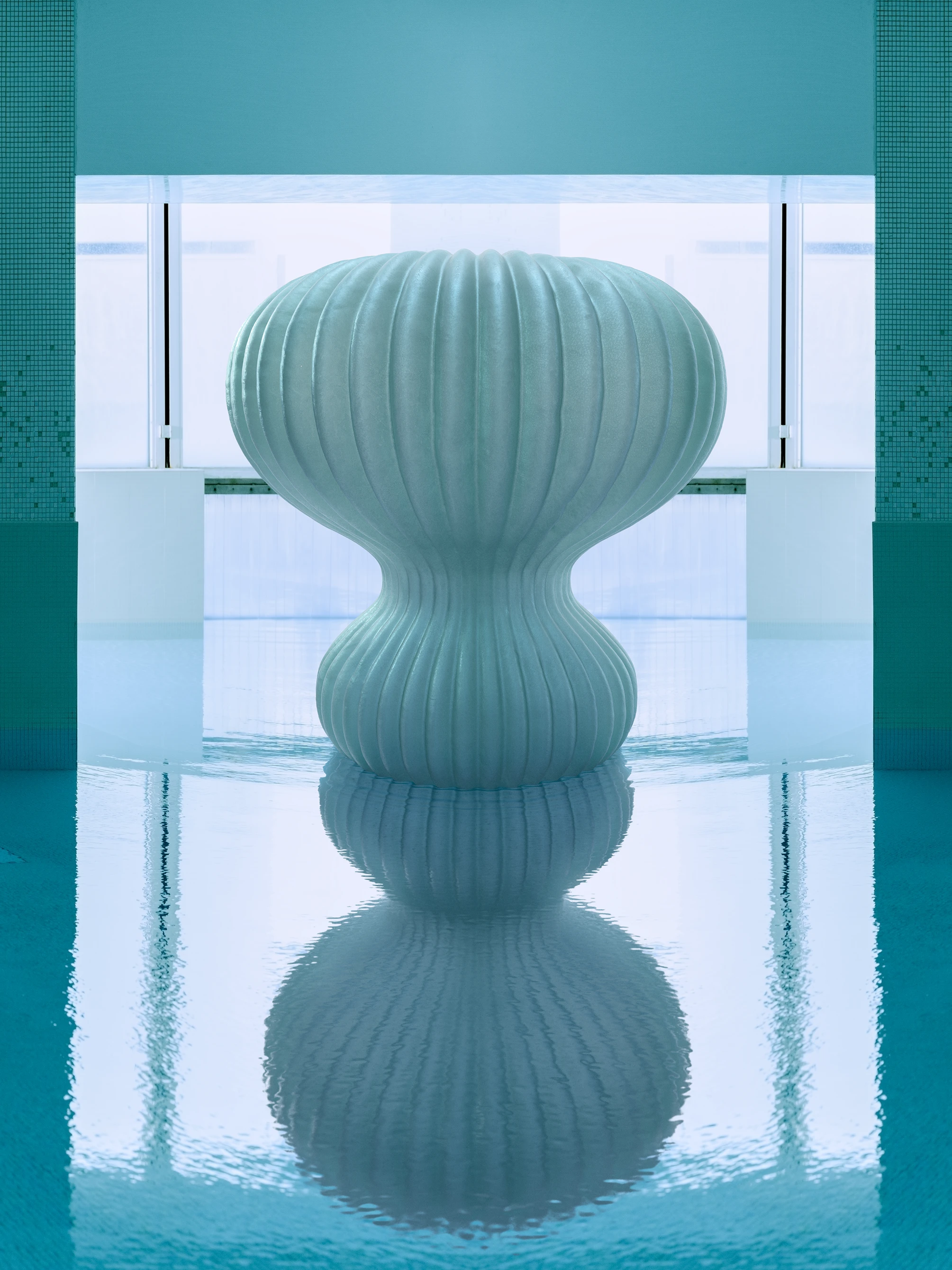 Ribbed sculptural side table in pale celadon, reflected in still pool water amid a serene aqua interior