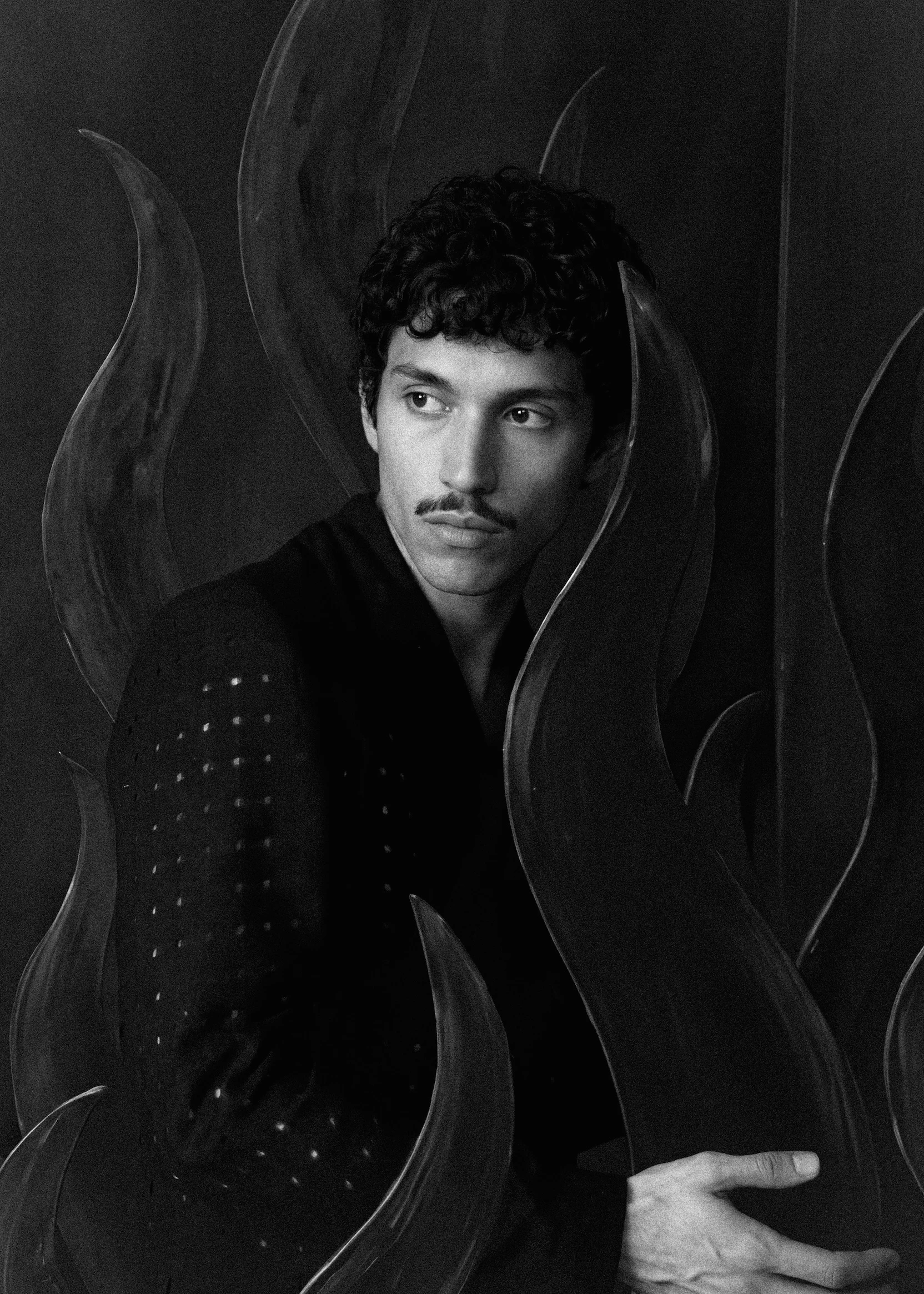 Goksenin Ay in the Lament collection, black jacket with stud detail, surrounded by flame-shaped sculptural panels