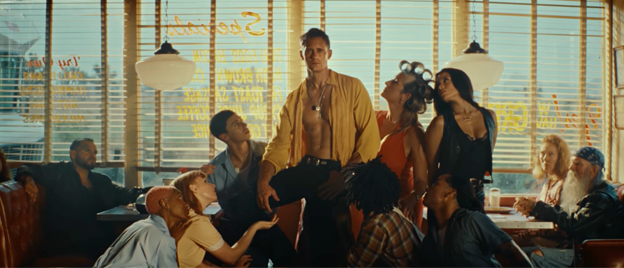 Alexander Skarsgard stands shirtless in a retro diner surrounded by townspeople in The Rolling Stones' Mr. Charm music video.