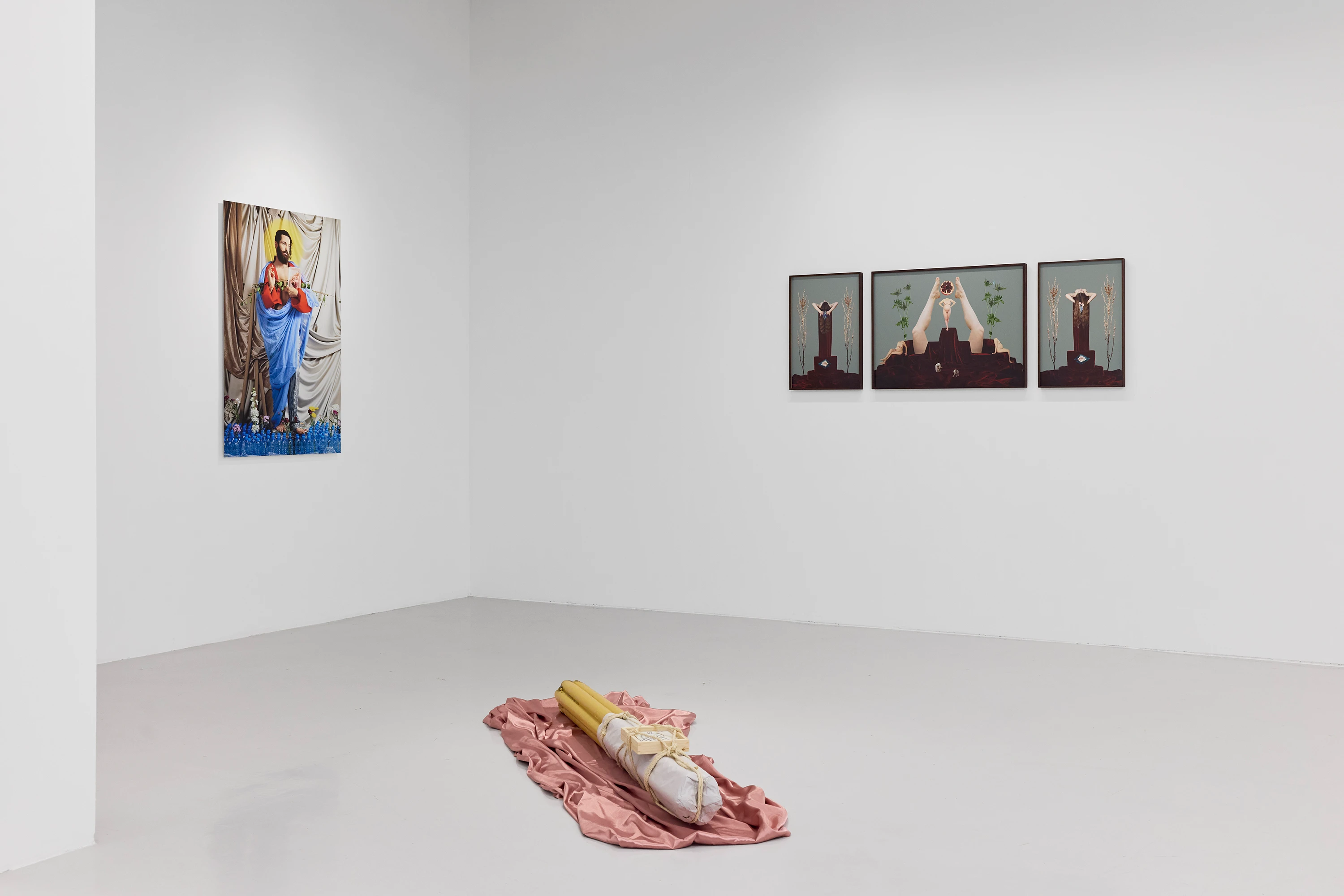 Installation view of Offrandes group show at NIKA Project Space, featuring religious iconography prints and floor sculpture