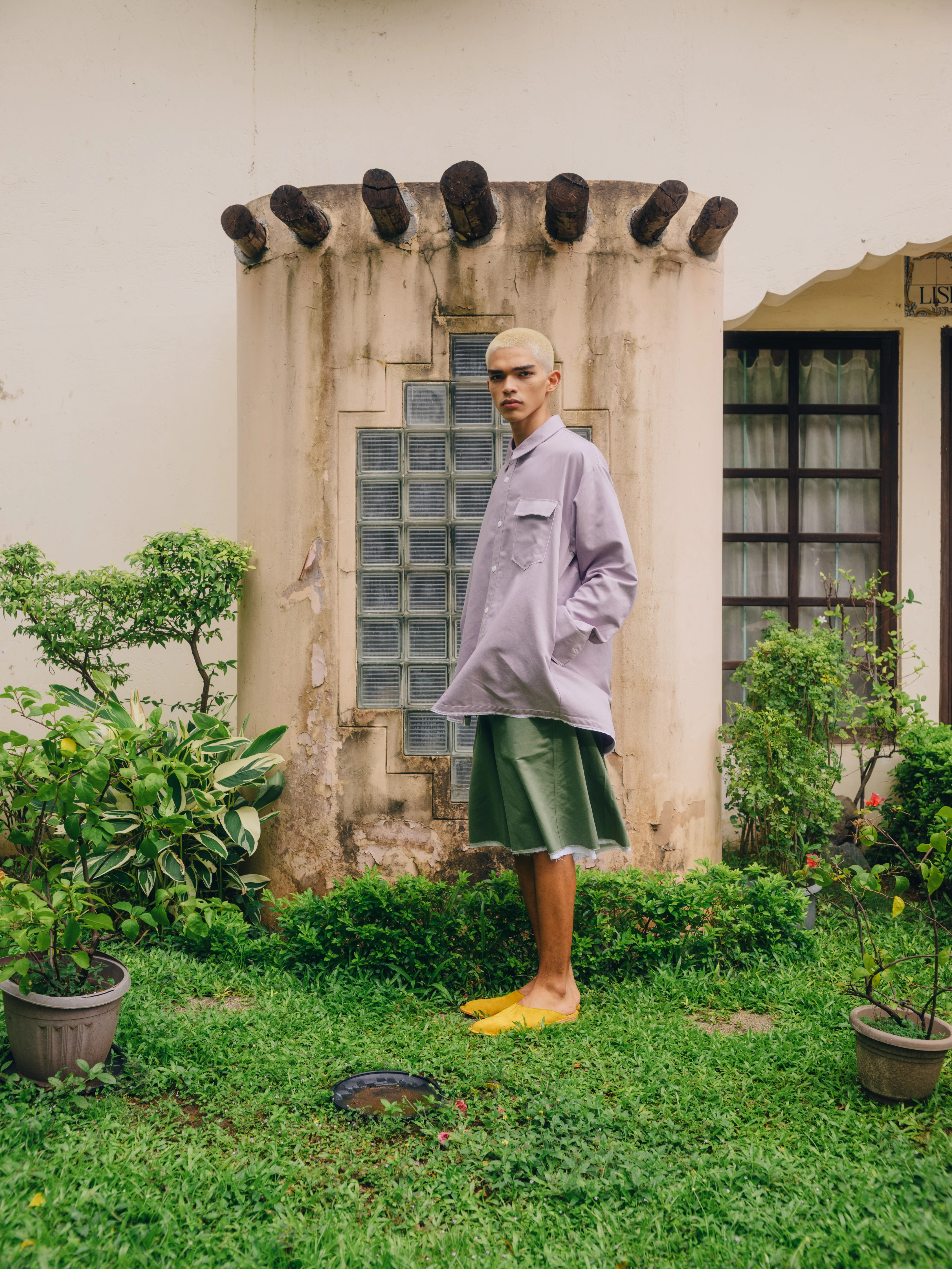 BAGASAO oversized lavender shirt green midi skirt yellow slides model standing tropical garden