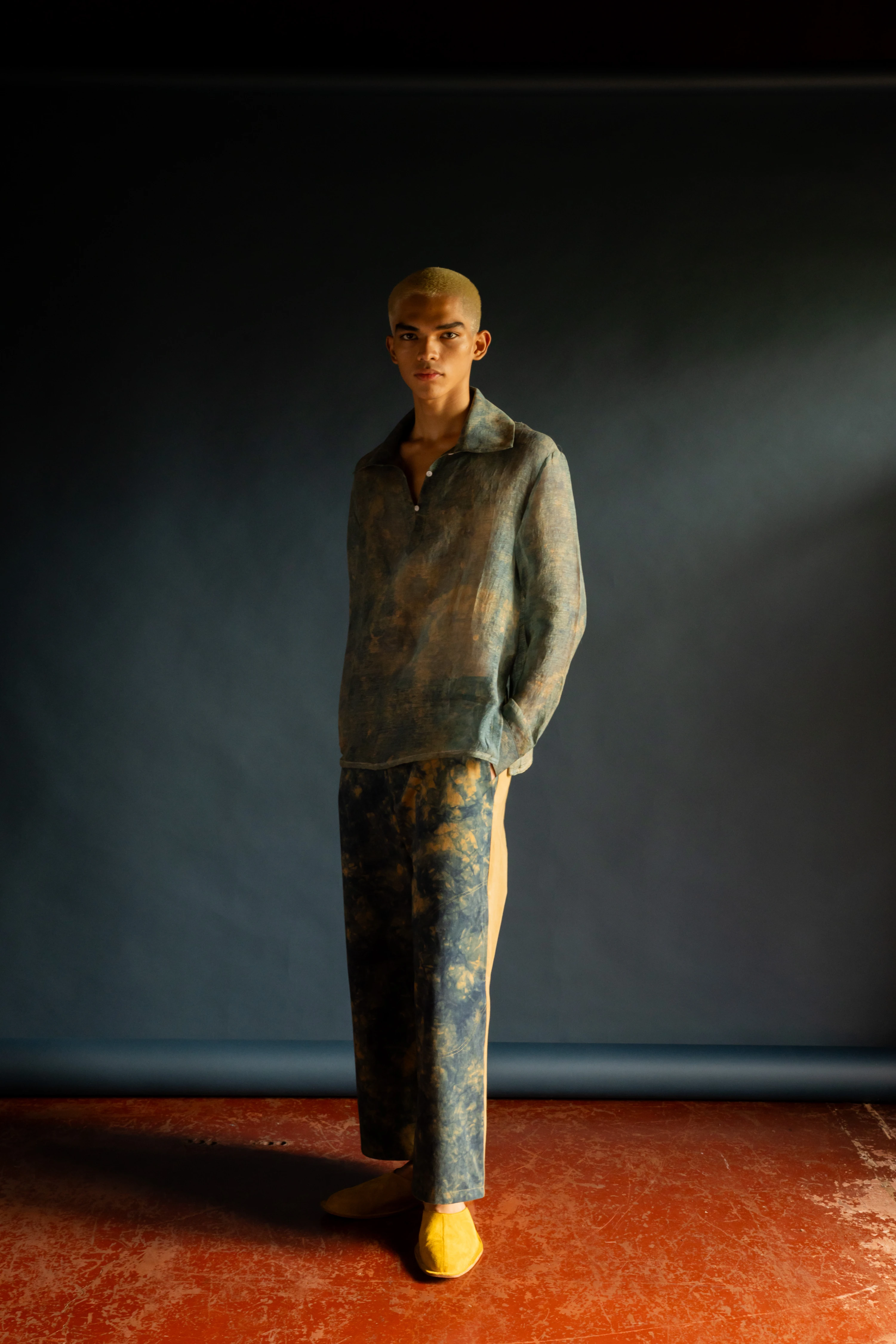 BAGASAO model wearing tie-dye linen co-ord set with yellow shoes against dark studio backdrop