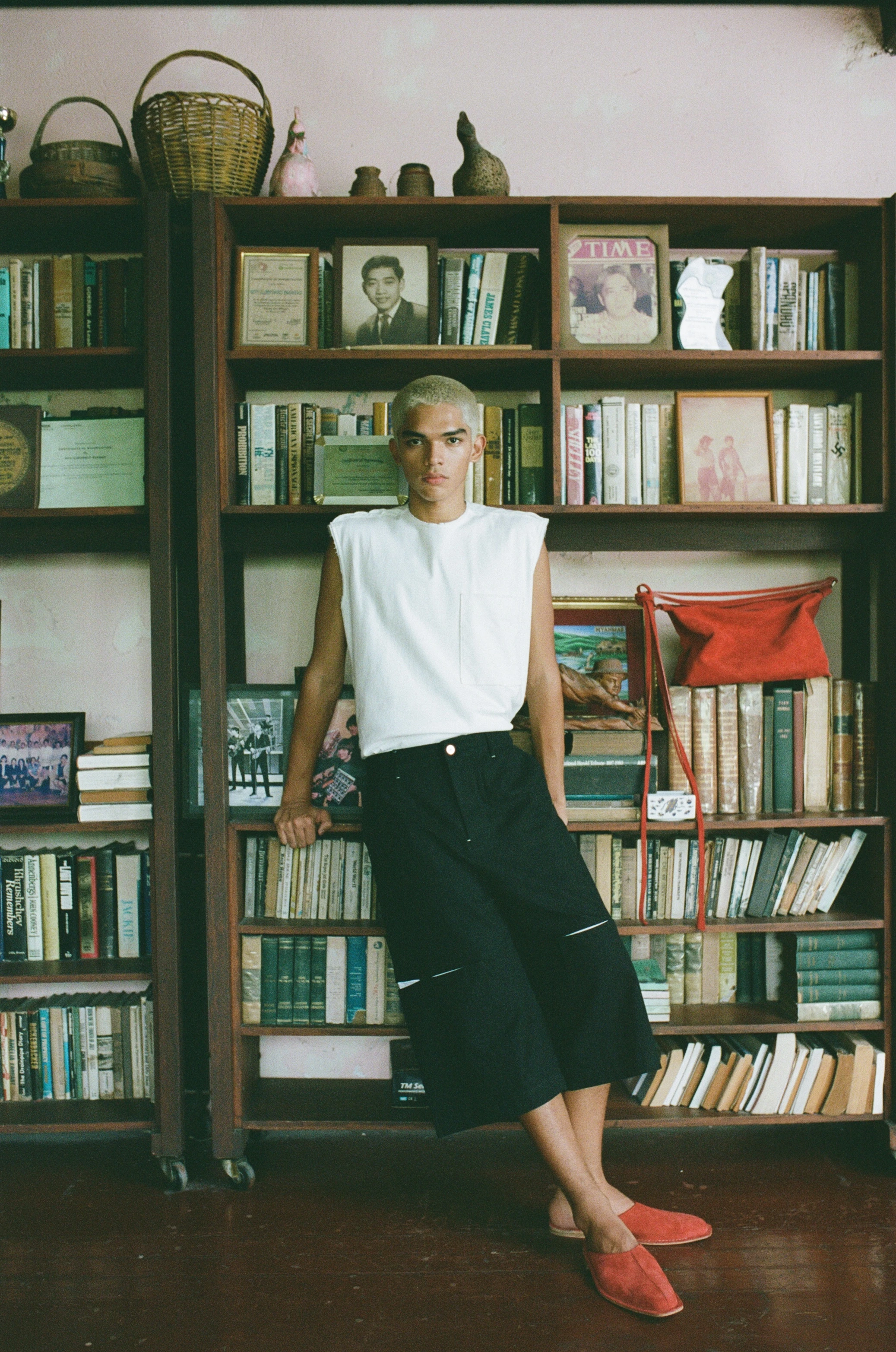 BAGASAO model in white sleeveless top and black wide-leg trousers poses before a richly stocked bookshelf